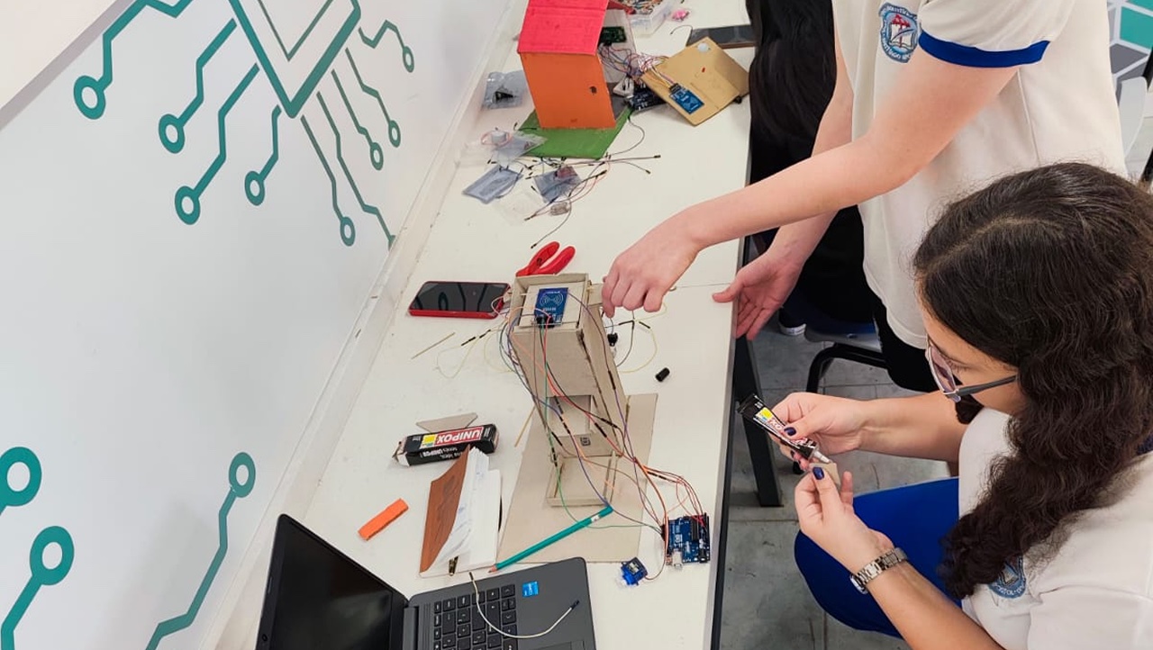 Estudiantes armando un proyecto con placa Arduino y cables en el aula maker