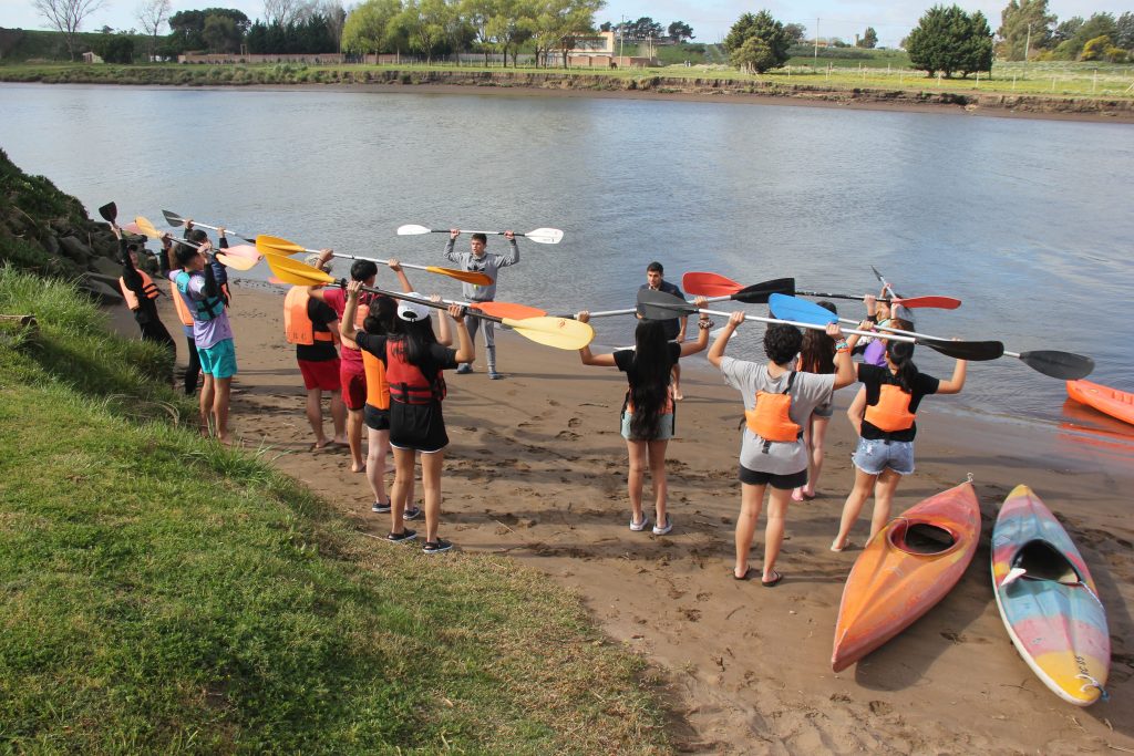 Estudiantes con kayaks a orillas del río durante el campamento